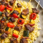 Juicy beef and vegetable skewers served over orzo pasta, flavorful grilled meat, colorful grilled vegetables, perfect for easy delicious summer recipes, healthy dinner ideas, and barbecue meals.