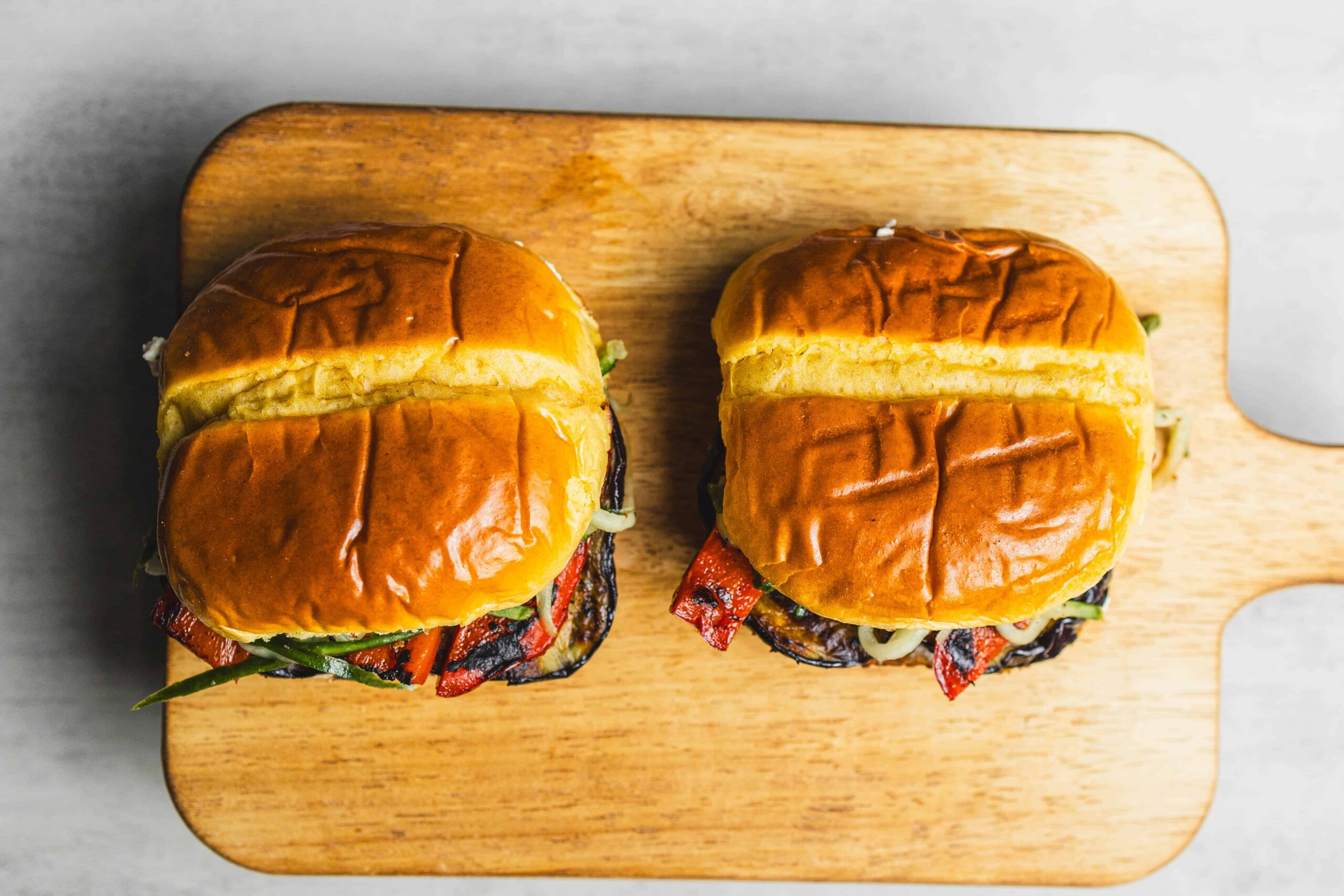 Crispy grilled veggie burgers with fresh toppings on a wooden cutting board, served as vegetarian fast food or plant-based meal options vegan friendly and delicious.