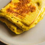 Golden brown French toast with crispy edges on a white plate, topped with a hint of butter and cinnamon. Perfect for breakfast or brunch, this delicious recipe offers a soft interior with a crispy exterior.