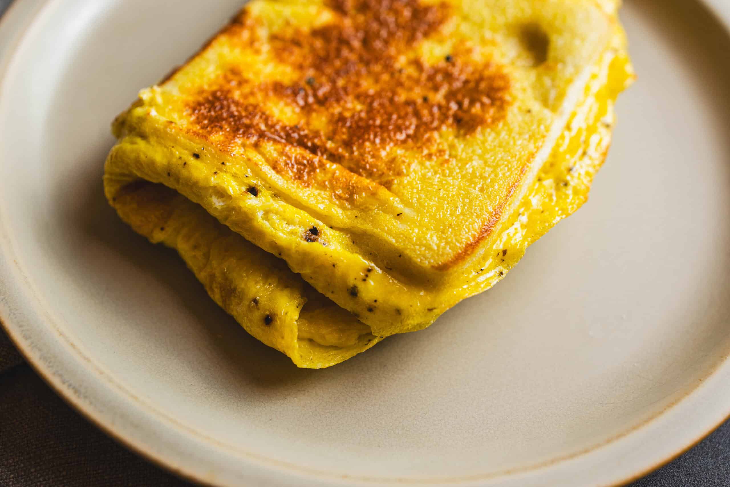 Golden brown French toast with crispy edges on a white plate, topped with a hint of butter and cinnamon. Perfect for breakfast or brunch, this delicious recipe offers a soft interior with a crispy exterior.