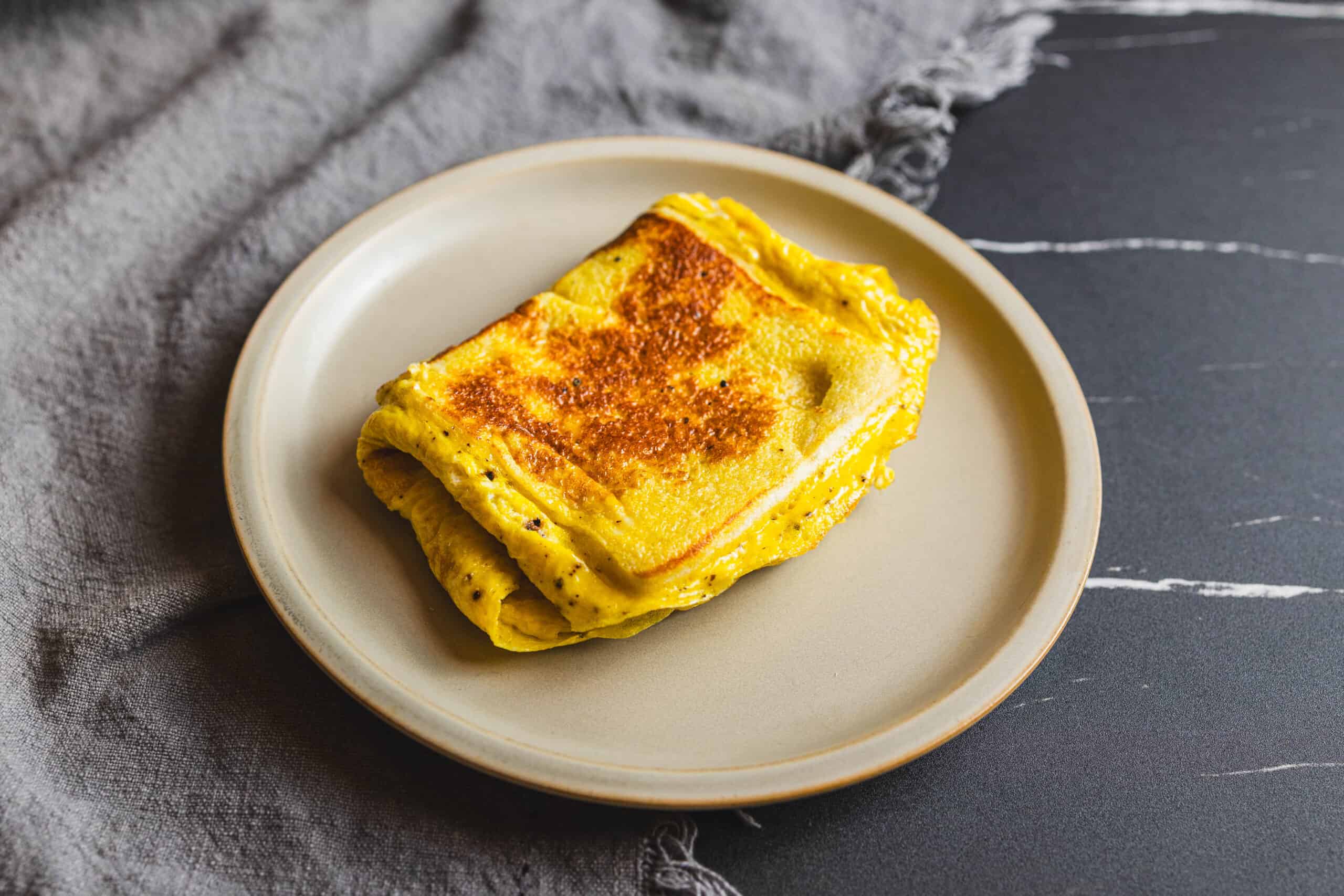 Savory scrambled eggs, golden-brown and cooked to perfection on a white plate, served as a delicious breakfast or brunch option.
