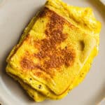 Fluffy golden scrambled eggs with crispy edges on a white plate, perfect for a delicious breakfast or brunch. Prepared with fresh ingredients, offering a creamy texture and rich flavor.