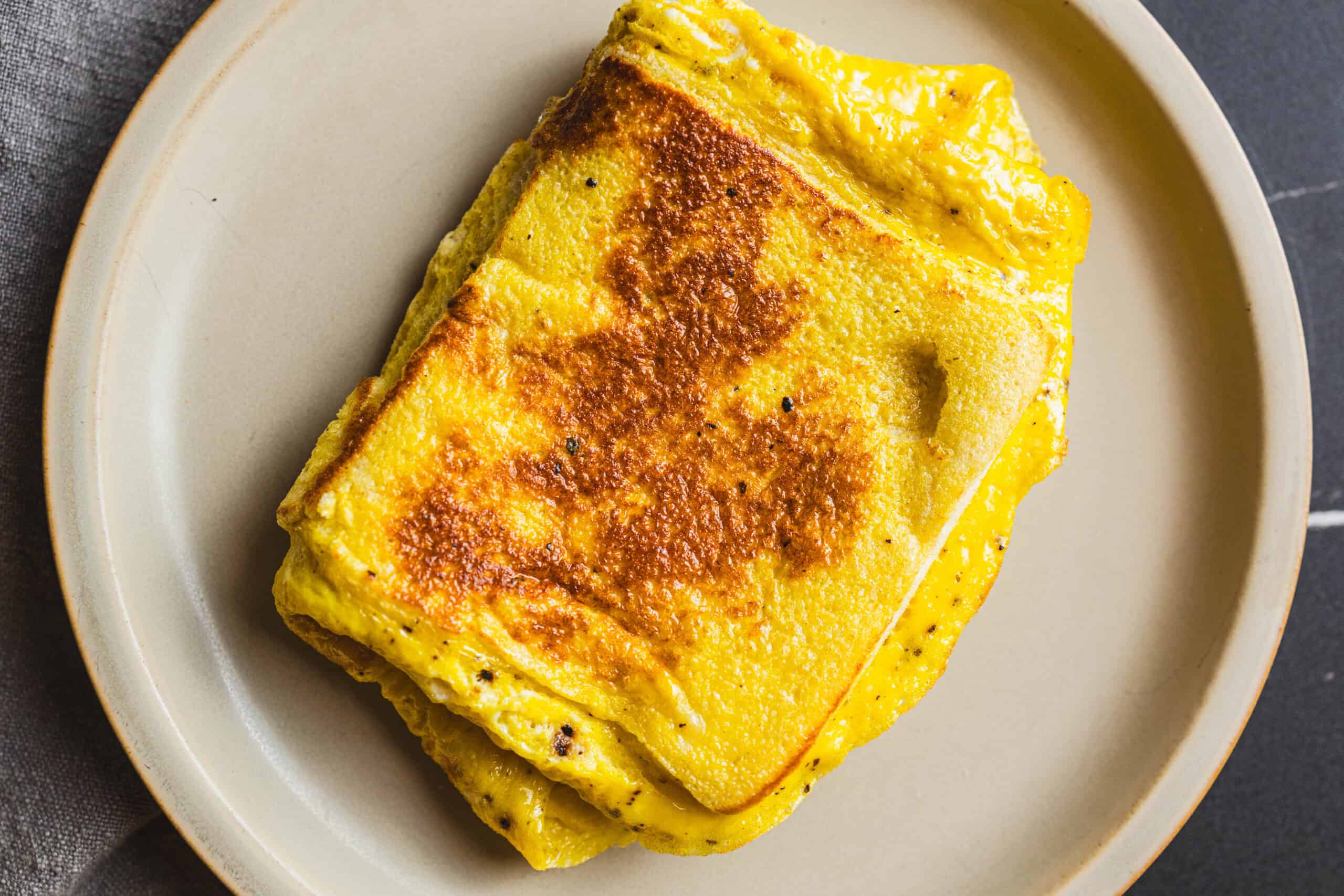 Fluffy golden scrambled eggs with crispy edges on a white plate, perfect for a delicious breakfast or brunch. Prepared with fresh ingredients, offering a creamy texture and rich flavor.