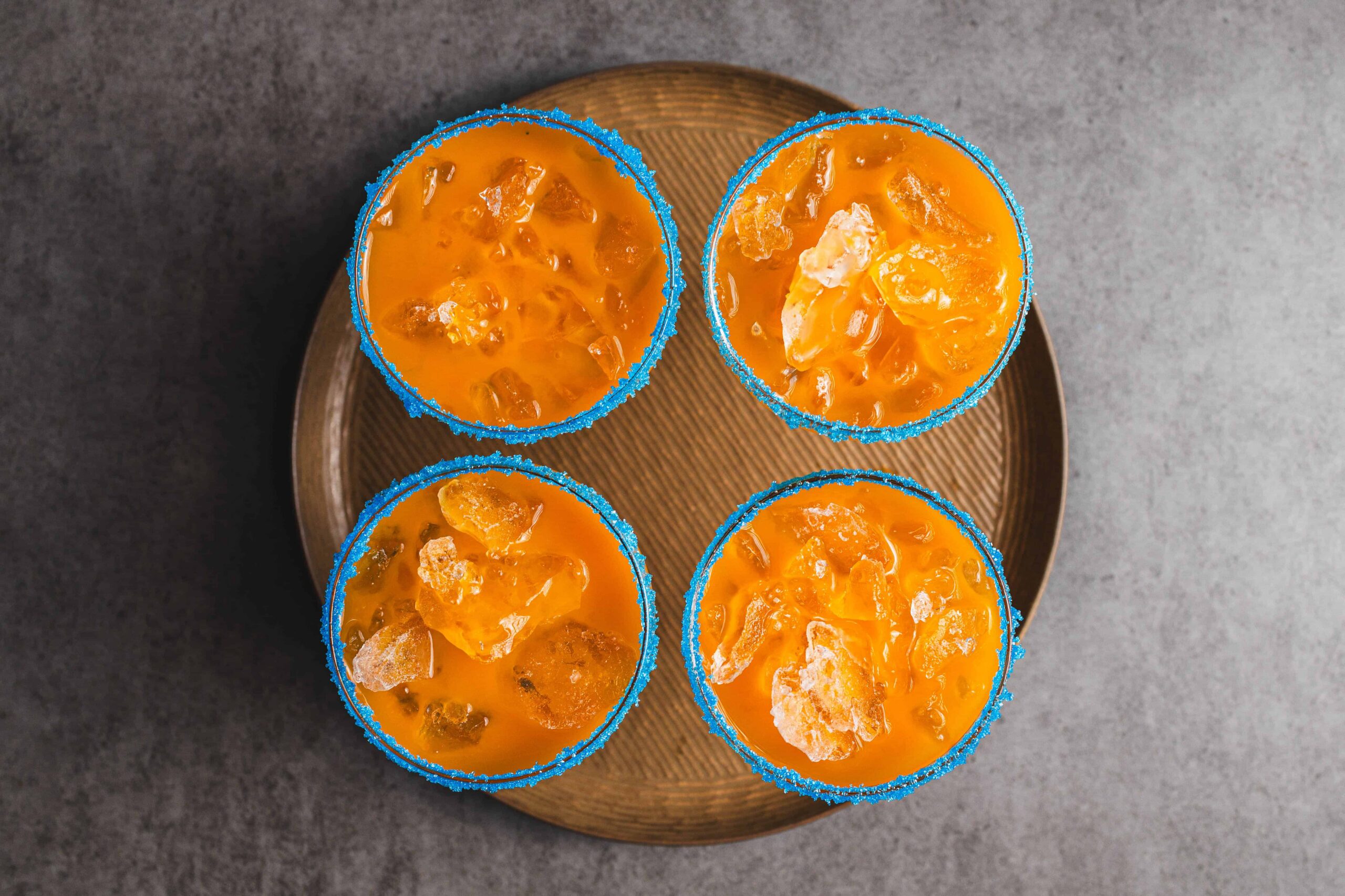 Sweet and tangy mango margaritas with salted rim, served in blue sugar-coated glasses, perfect for summer parties and outdoor celebrations.