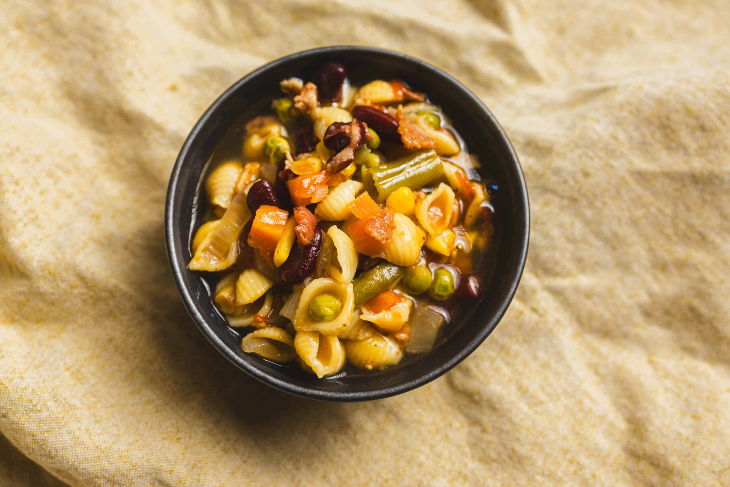 Creamy vegetable pasta soup with pasta shells, carrots, peas, corn, kidney beans, and celery in a broth. Healthy, hearty, and flavorful vegetable soup perfect for any season.