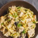 Creamy chicken pasta with herbs, vegetables, and black pepper in a brown bowl, ready to serve.