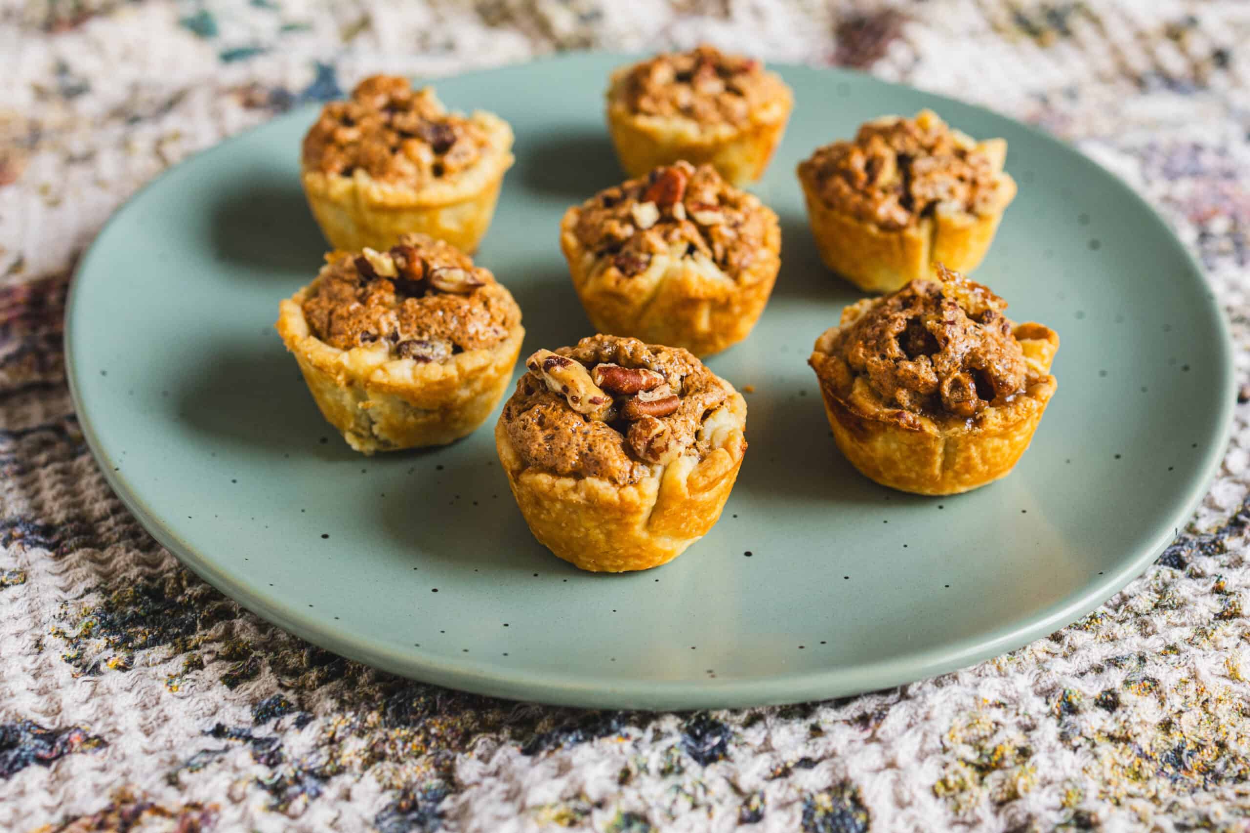 Cream cheese stuffed mini muffins with a crumb topping on a light blue plate, perfect for breakfast or snack, featuring a golden crust and moist texture.