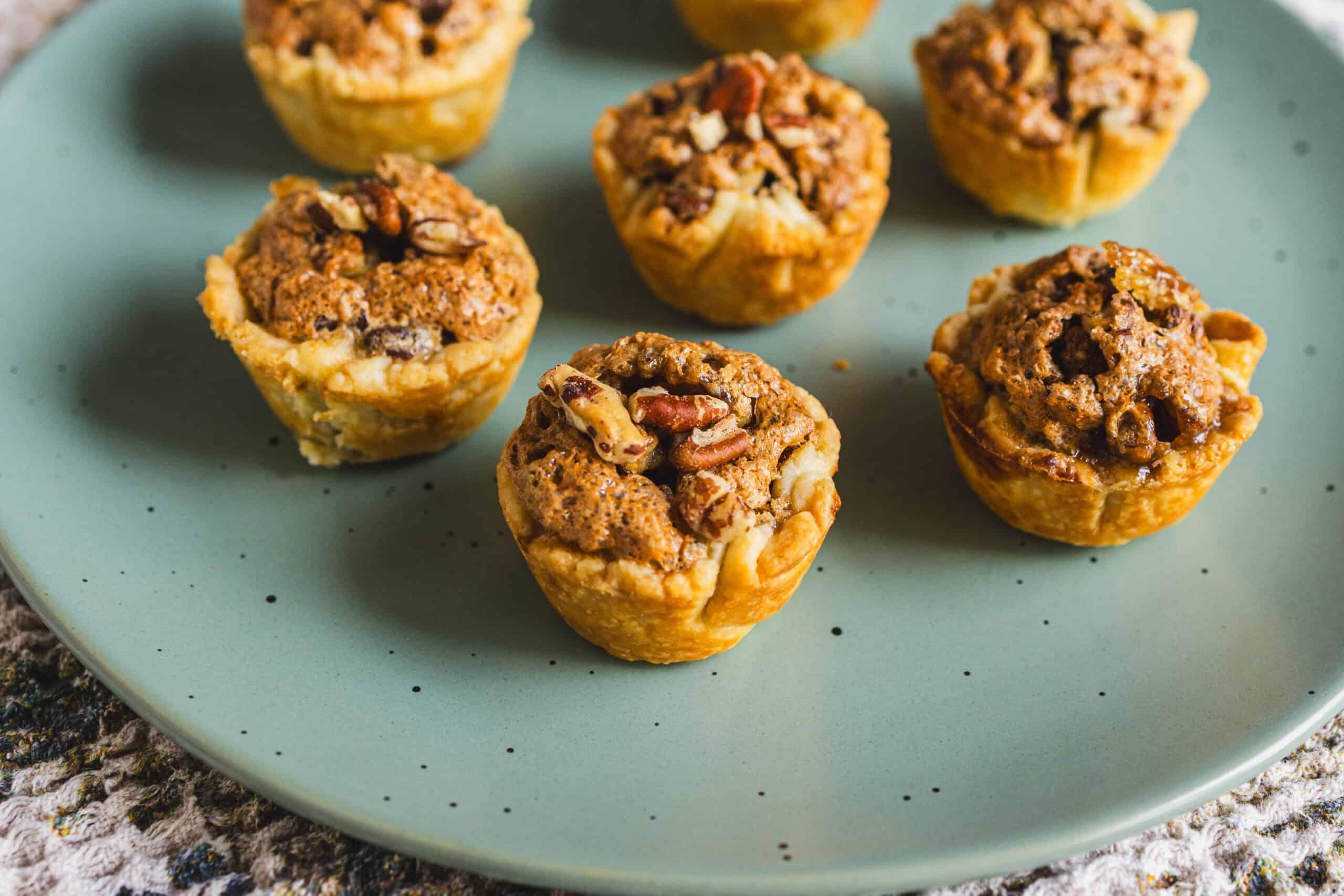 Chocolate chip muffin cups with crunchy crumble topping on a mint green plate, perfect for breakfast or snack. Homemade muffin cups filled with rich chocolate chips and a crispy topping.