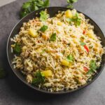 Steamed vegetable fried rice dish with colorful vegetables and fresh cilantro garnished on top.