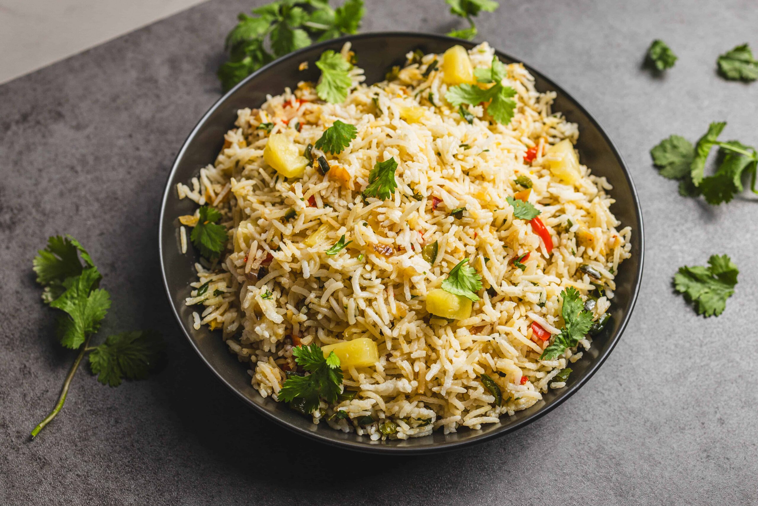 Steamed vegetable fried rice dish with colorful vegetables and fresh cilantro garnished on top.