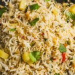 Fragrant vegetable fried rice with pineapple, cilantro, and colorful bell peppers served in a black bowl. Perfect for a quick, healthy, and flavorful meal or side dish.
