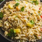 Steamed rice with vegetables and fresh herbs served in a black bowl, showcasing a flavorful and colorful rice dish perfect for healthy meals and easy recipes.