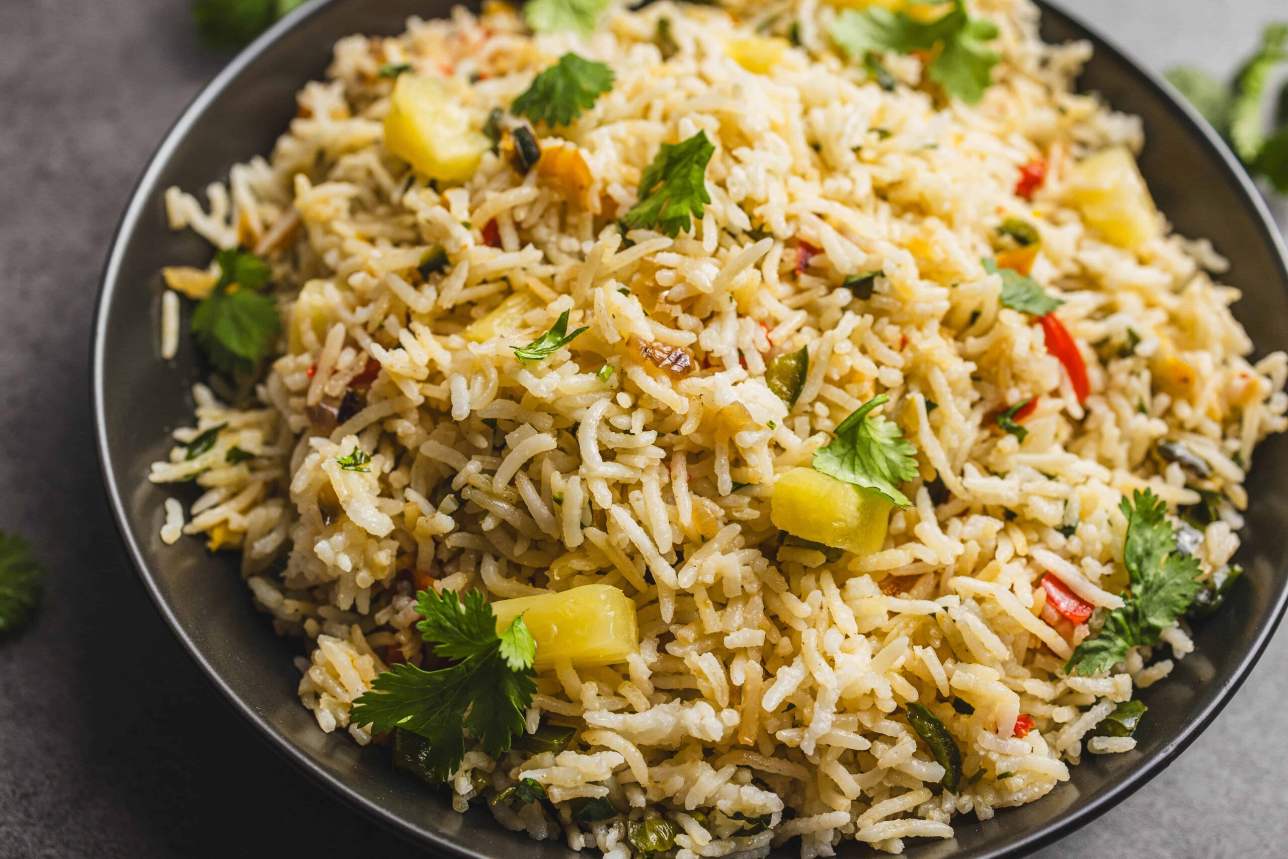 Steamed rice with vegetables and fresh herbs served in a black bowl, showcasing a flavorful and colorful rice dish perfect for healthy meals and easy recipes.