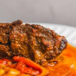 Juicy beef meatloaf with savory tomato-based sauce served on a white plate, highlighting a delicious homemade comfort food meal.