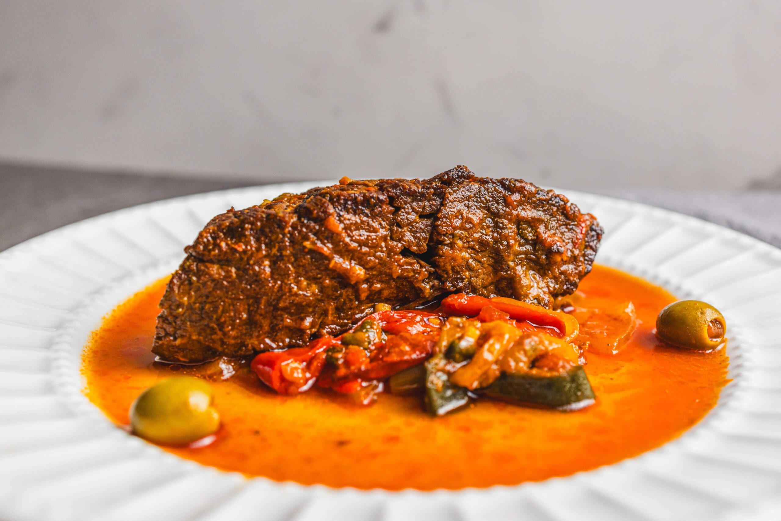 Braised beef stew with vegetable sauce served on a white plate; hearty, flavorful, and perfect for comfort food recipes.