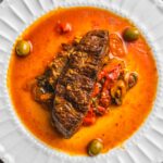 Freshly cooked beef stew with vegetables in rich, flavorful sauce served on a white ceramic plate. Perfect comfort food for dinner.