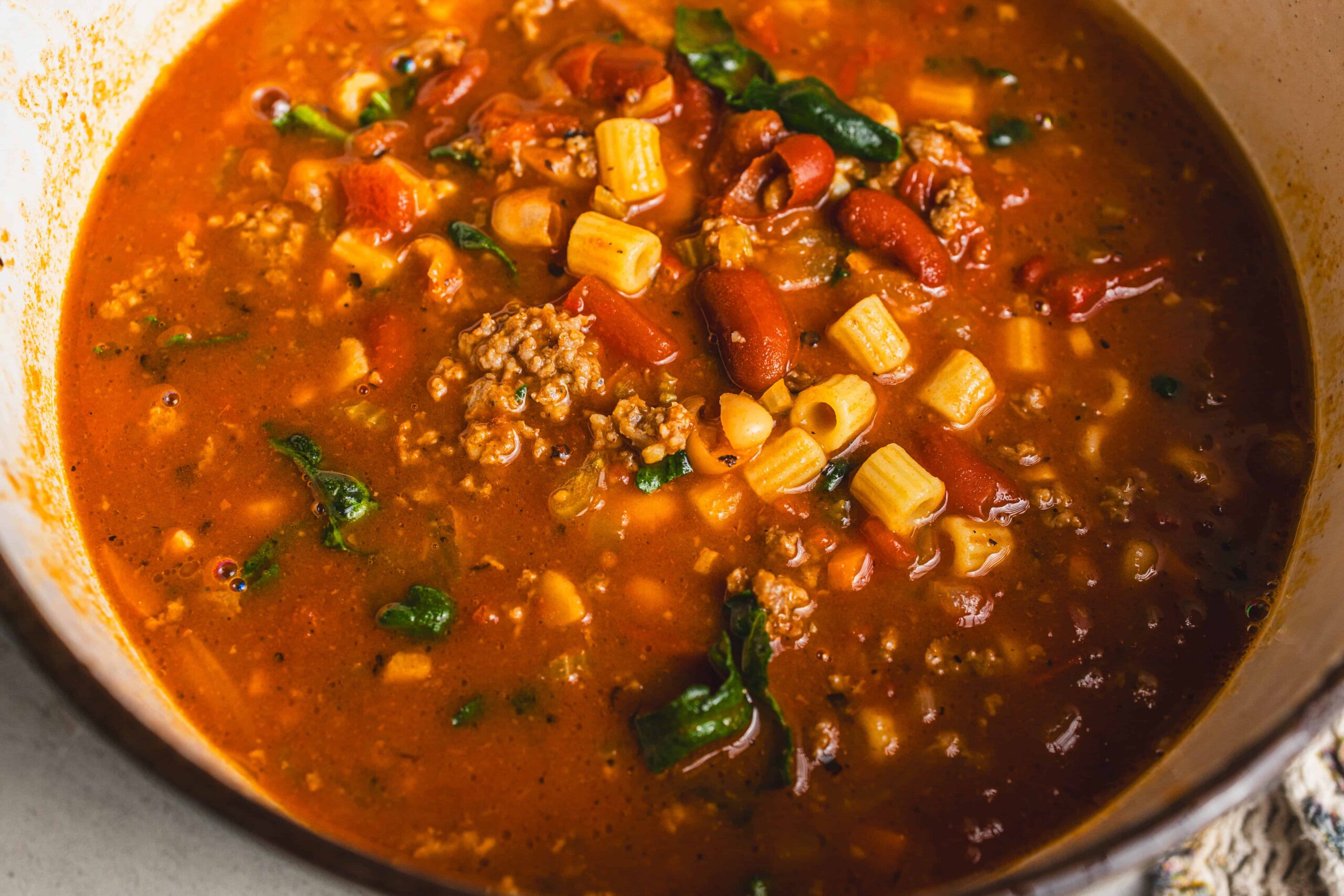 Savory homemade beef and vegetable chili in a pot with tomatoes, ground beef, kidney beans, corn, and spices, ready to serve as a hearty, flavorful meal.
