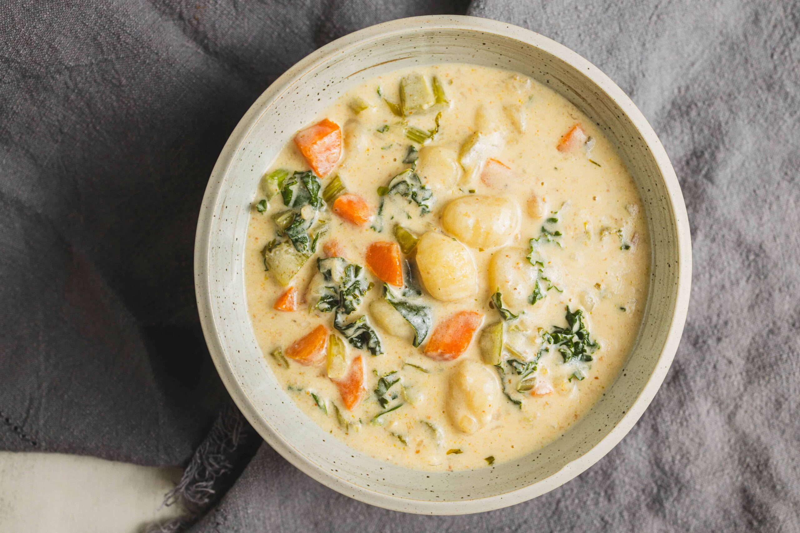 Creamy vegetable chicken soup with carrots, potatoes, celery, and kale in a bowl, perfect for comfort food and healthy eating.