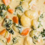 Creamy vegetable potato soup with carrots, kale, and herbs in a close-up shot.
