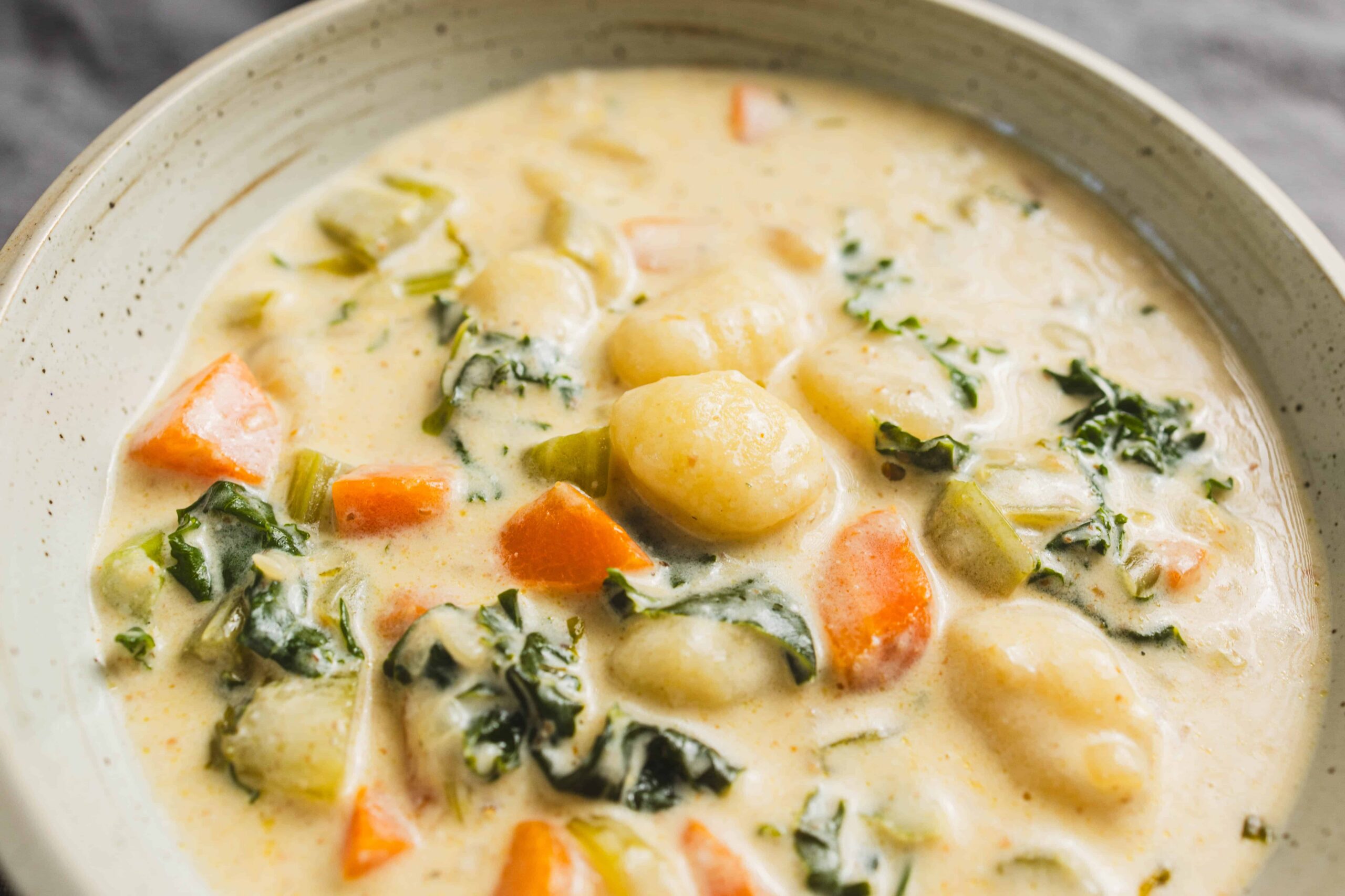 Creamy vegetable and potato stew with carrots, kale, and herbs in a rustic bowl for a comforting, hearty meal. Perfect for cold days or when craving healthy, flavorful comfort food.