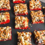 Sweet snowball dessert bars topped with white chocolate, chopped pecans, and a layered red velvet base, perfect for holiday treats and sweet snack recipes.