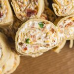 Cream cheese and bacon stuffed chicken roll-ups sliced open to show a creamy filling with bacon and green onion bits, perfect as a savory appetizer or main dish.