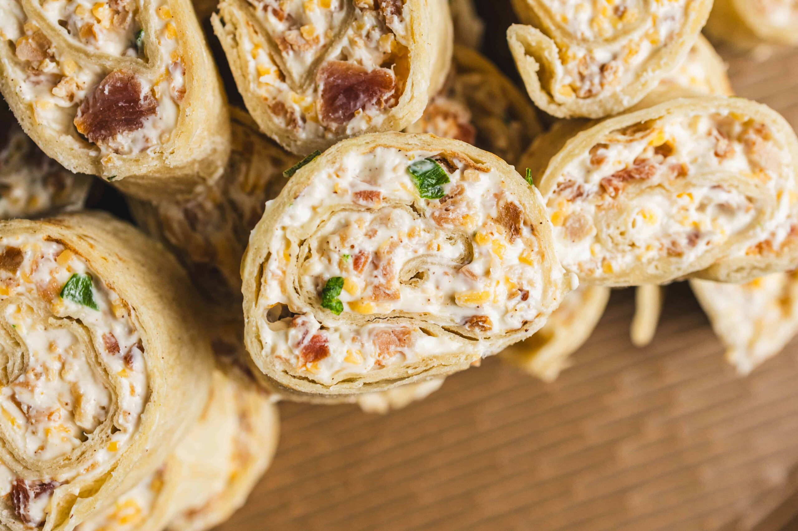 Cream cheese and bacon stuffed chicken roll-ups sliced open to show a creamy filling with bacon and green onion bits, perfect as a savory appetizer or main dish.