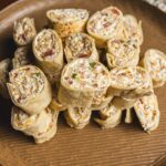 Scrambled egg and bacon breakfast burritos sliced into spirals, arranged on a round wooden plate. Perfect for quick breakfast ideas and savory brunch recipes.